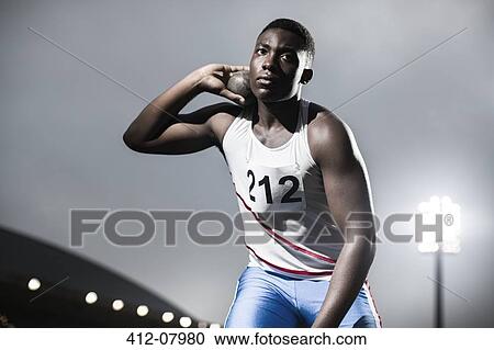 Stock Image - Track and field athlete holding shot put. Fotosearch