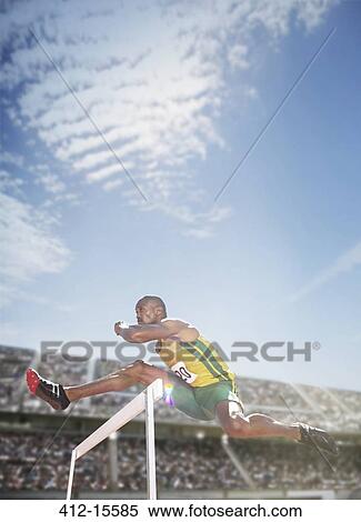 Stock Photography - Track and field athlete jumping hurdle. Fotosearch