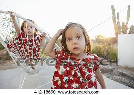 Stock Image - Twin baby girls playing on patio. Fotosearch