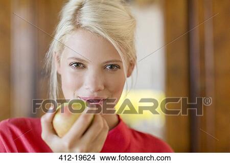 Woman eating apple indoors View Large Photo Image Picture - Woman eating apple indoors. Fotosearch
