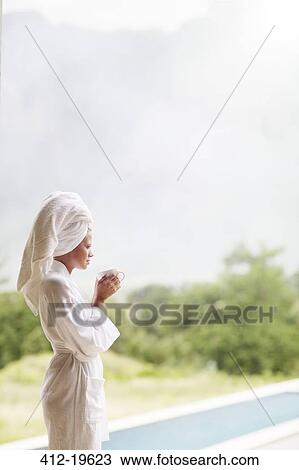 Stock Image - Woman in bathrobe drinking coffee outdoors. Fotosearch