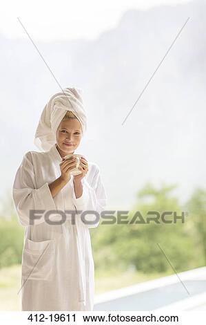 Stock Image - Woman in bathrobe having coffee outdoors. Fotosearch