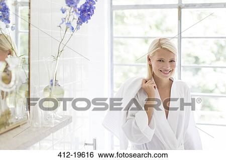 Stock Photograph - Woman in bathrobe smiling in bathroom. Fotosearch