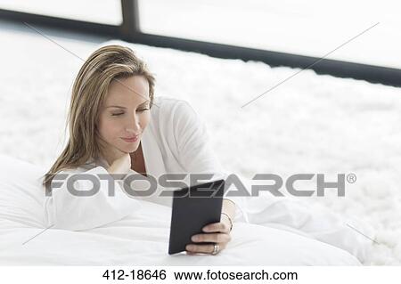 Woman in bathrobe using digital tablet in bedroom View Large Photo Image Stock Photograph - Woman in bathrobe using digital tablet in bedroom. Fotosearch