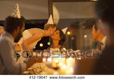 Stock Photo - Woman kissing friends cheek at birthday party. Fotosearch