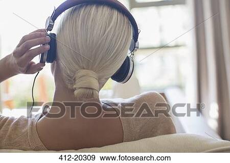 Woman listening to headphones on sofa View Large Photo Image Stock Photo - Woman listening to headphones on sofa. Fotosearch