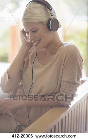 Woman listening to headphones on sofa View Large Photo Image Stock Photograph - Woman listening to headphones on sofa. Fotosearch