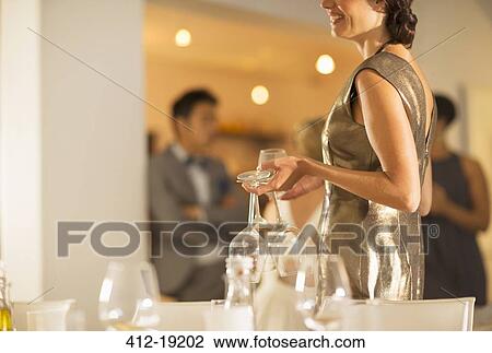 Stock Image - Woman setting table at dinner party. Fotosearch