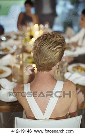 Woman sitting at dinner party View Large Photo Image Stock Photograph - Woman sitting at dinner party. Fotosearch