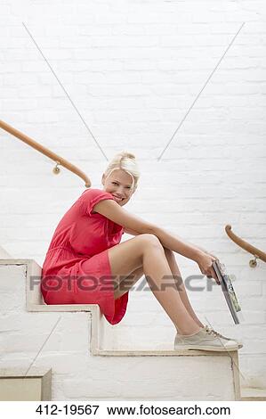 Woman sitting on steps of modern house View Large Photo Image Stock Photo - Woman sitting on steps of modern house. Fotosearch