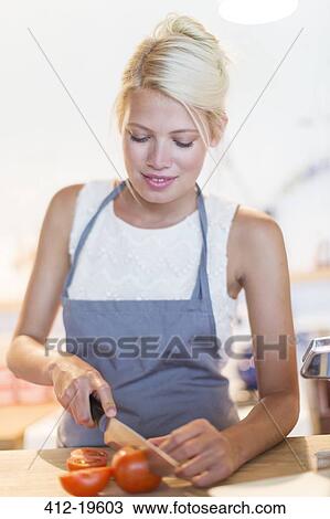 Stock Image - Woman slicing vegetables in kitchen. Fotosearch