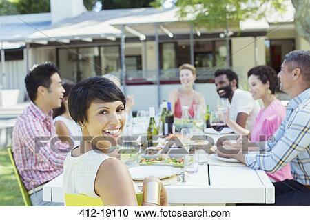 Stock Image - Woman smiling at table outdoors. Fotosearch