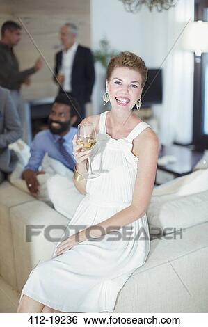 Woman smiling on sofa at party View Large Photo Image Stock Photograph - Woman smiling on sofa at party. Fotosearch