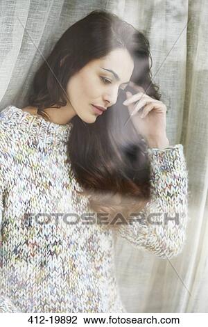 Stock Image - Woman standing by window. Fotosearch