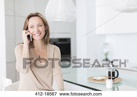 Woman talking on cell phone at breakfast table View Large Photo Image Stock Photo - Woman talking on cell phone at breakfast table. Fotosearch