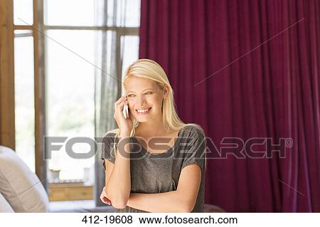 Stock Photo - Woman talking on cell phone in bedroom. Fotosearch