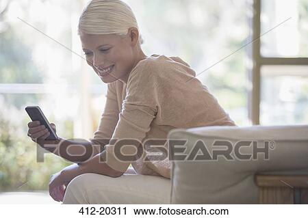 Woman using cell phone on sofa View Large Photo Image Stock Image - Woman using cell phone on sofa. Fotosearch