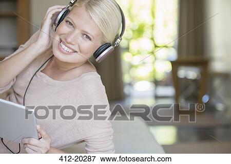 Stock Photo - Woman using digital tablet and headphones. Fotosearch
