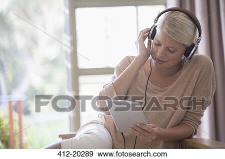 Stock Photo - Woman using digital tablet and headphones. Fotosearch
