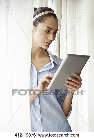 Stock Photograph - Woman using digital tablet at window. Fotosearch