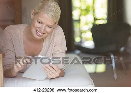 Woman using digital tablet on sofa View Large Photo Image Stock Photo - Woman using digital tablet on sofa. Fotosearch