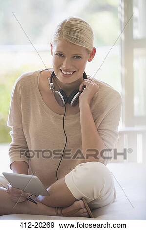 Stock Photo - Woman using digital tablet with headphones. Fotosearch