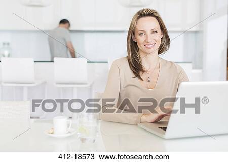 Woman using laptop at breakfast table View Large Photo Image Stock Image - Woman using laptop at breakfast table. Fotosearch