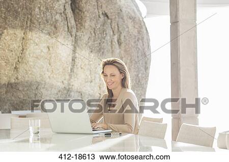 Woman using laptop at table View Large Photo Image Stock Image - Woman using laptop at table. Fotosearch