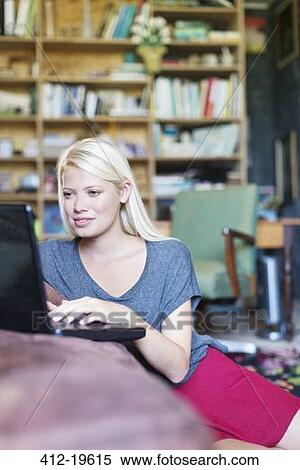 Woman using laptop in living room View Large Photo Image Stock Photography - Woman using laptop in living room. Fotosearch