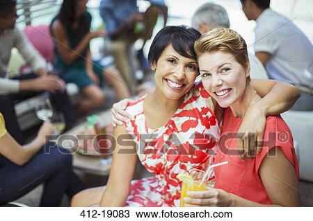 Stock Image - Women hugging at party. Fotosearch