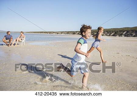 Children running in waves on beach View Large Photo Image Stock Photography - Children running in waves on beach . Fotosearch