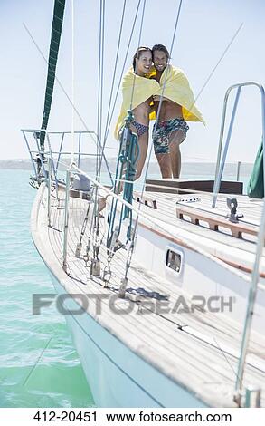 Stock Image - Couple sharing towel in boat on water . Fotosearch