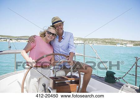 Stock Image - Couple steering boat together . Fotosearch