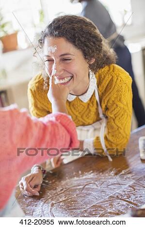 Stock Photography - Daughter putting flour on mother's nose. Fotosearch