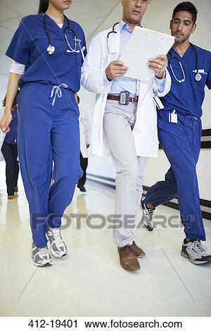 Doctor and nurses reading medical chart in hospital hallway View Large Photo Image Stock Image - Doctor and nurses reading medical chart in hospital hallway. Fotosearch