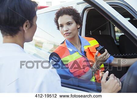 Stock Image - Doctor and paramedic talking outside ambulance. Fotosearch