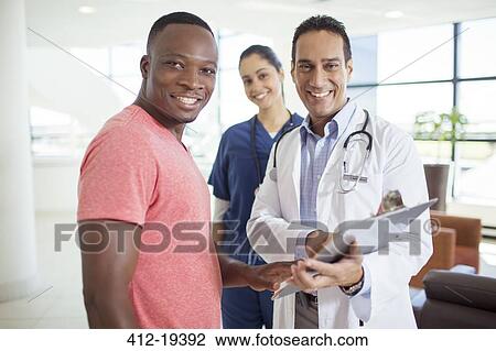 Stock Image - Doctor and patient smiling in hospital. Fotosearch