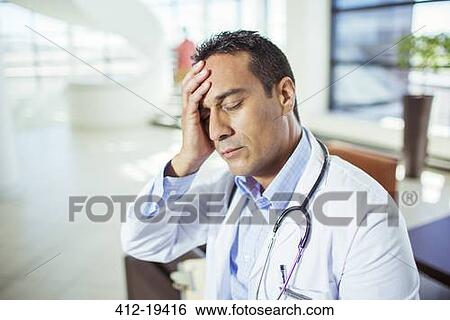 Stock Photograph - Doctor holding his forehead in hospital. Fotosearch