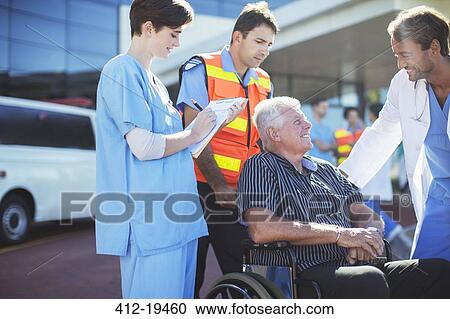 Stock Image - Doctor, nurse and paramedic talking to patient outside hospital. Fotosearch
