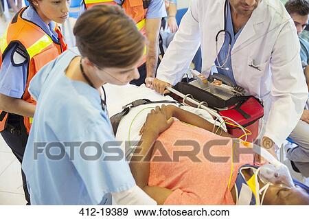 Stock Photo - Doctor, nurse and paramedics examining patient on stretcher. Fotosearch