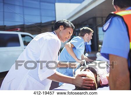 Stock Photo - Doctor, nurse and paramedics wheeling patient to hospital. Fotosearch