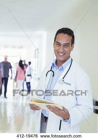 Doctor reading medical chart in hospital hallway View Large Photo Image Stock Photograph - Doctor reading medical chart in hospital hallway. Fotosearch