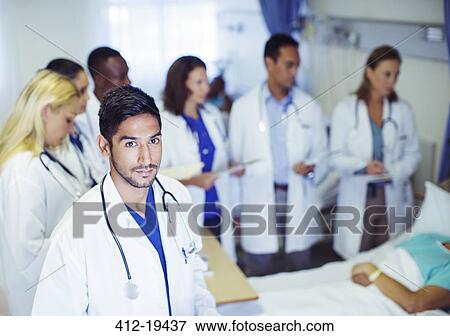 Stock Photo - Doctor standing with residents in hospital room. Fotosearch