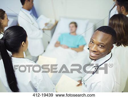 Stock Photograph - Doctor standing with residents in hospital room. Fotosearch - Search Stock Photography, Posters, Pictures, and Photo Clipart Images