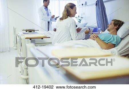 Stock Image - Doctor talking to patient in hospital bed. Fotosearch