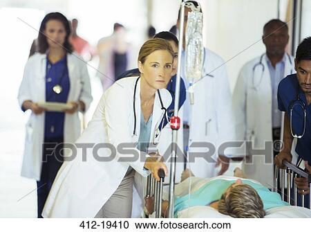 Doctors and nurses wheeling patient in hospital hallway View Large Photo Image Stock Image - Doctors and nurses wheeling patient in hospital hallway. Fotosearch