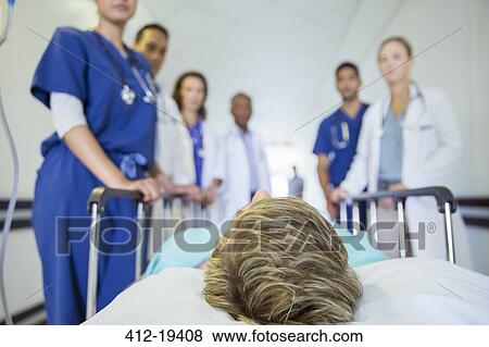 Doctors and nurses wheeling patient in hospital hallway View Large Photo Image Stock Photo - Doctors and nurses wheeling patient in hospital hallway. Fotosearch