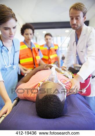Doctors and nurses wheeling patient down hospital hallway View Large Photo Image Stock Photograph - Doctors and nurses wheeling patient down hospital hallway. Fotosearch