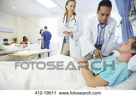 Doctors examining patient in hospital room View Large Photo Image Stock Image - Doctors examining patient in hospital room. Fotosearch