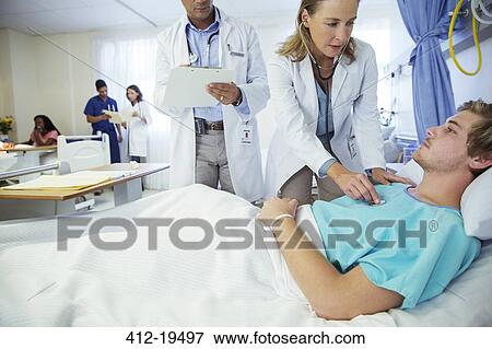 Doctors examining patient in hospital room View Large Photo Image Stock Photo - Doctors examining patient in hospital room. Fotosearch